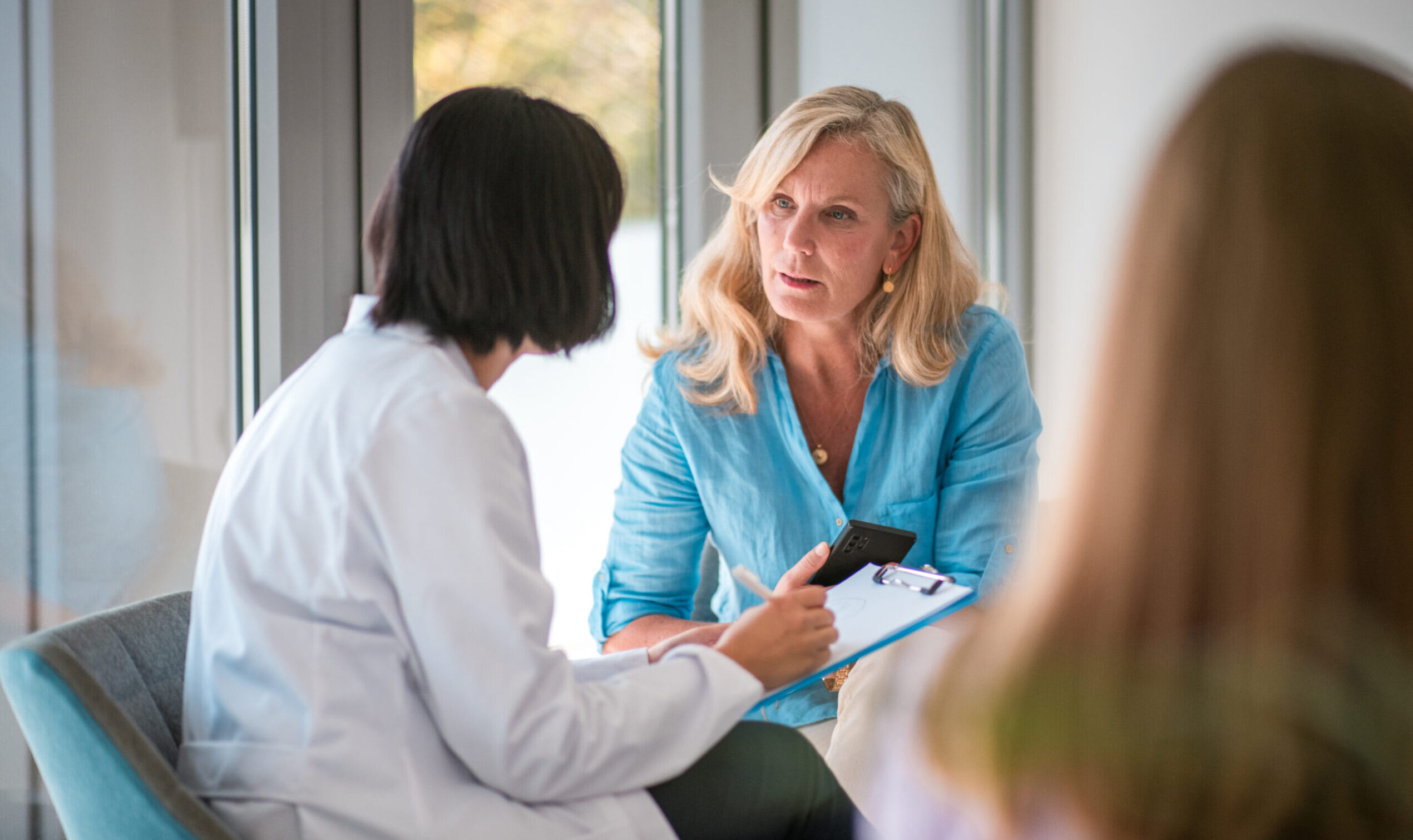 Mature Caucasian Female Patient Waiting and Consulting Asian Female Doctor